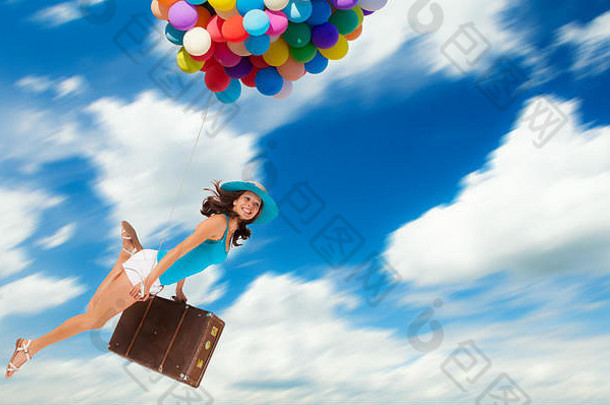 年轻的女人持有气球手提箱飞行云概念旅行自由