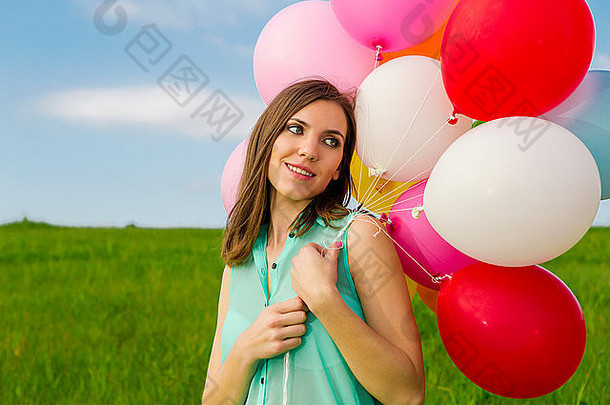 年轻的美丽的女人色彩斑斓的气球<strong>绿色</strong>草地