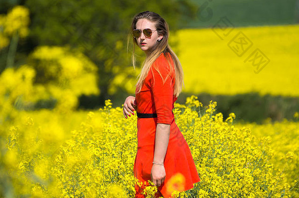 年轻的女人穿红色的衣服黄色的字段油菜籽