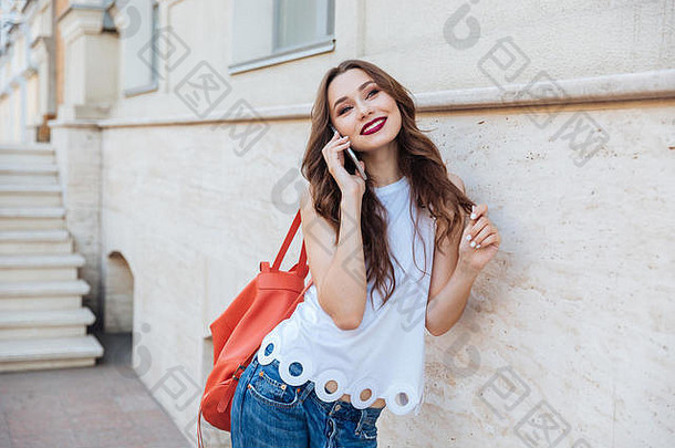 快乐快乐的年轻的女孩会说话的电话站在户外