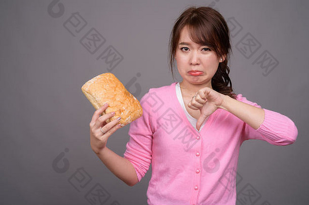 年轻的美丽的亚洲女人持有一块面包