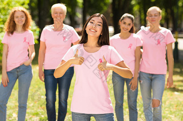女孩手势竖起大拇指前面乳房癌症志愿者集团户外