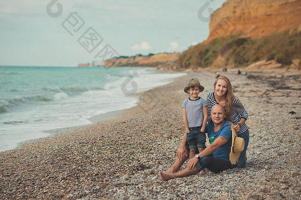 可爱的令人惊异的场景快乐家庭英俊的父亲美丽的夫人妈妈。可爱的儿子男孩摆姿势海一边海洋石头海滩
