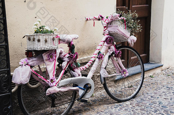 自行车装饰花粉红色的面料丝带停墙行人街小镇阿尔盖罗撒丁岛意大利