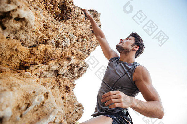 男人。达到控制岩石爬陡峭的悬崖