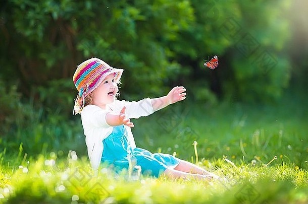 快乐笑女孩穿蓝色的衣服色彩斑斓的稻草他玩飞行蝴蝶有趣的花园
