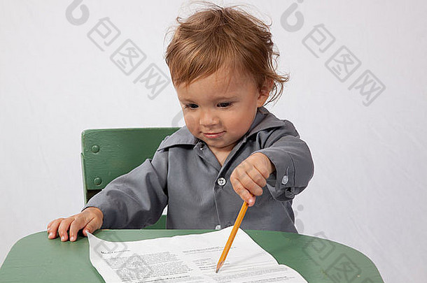 年轻的男孩坐着桌子上表纸铅笔快乐