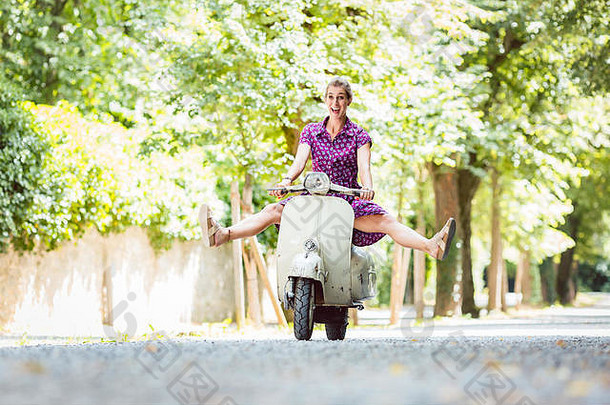 无忧无虑的年轻的女人开车踏板车