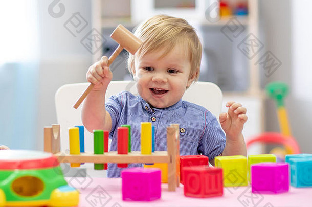 可爱的蹒跚学步的婴儿男孩玩木锤块玩具