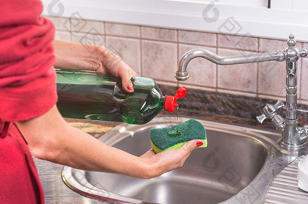 女人红色的修指甲把洗涤剂泻药洗菜