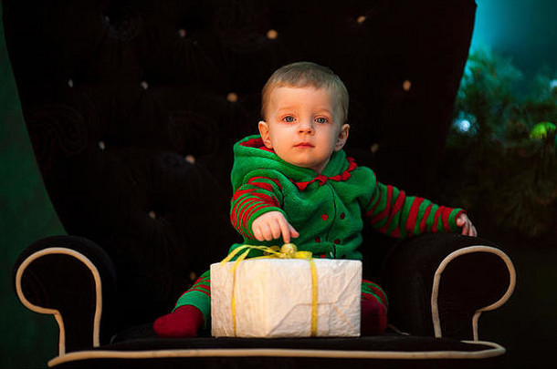 男孩坐在黑色的扶手椅延伸手盒子圣诞节礼物