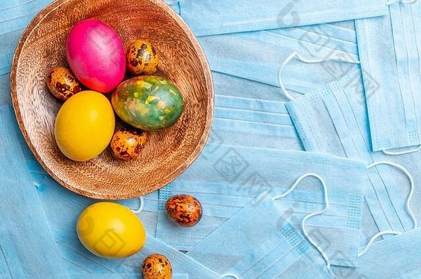 彩色的复活节鸡蛋木板背景蓝色的医疗面具科维德平躺复活节假期概念检疫冠状病毒
