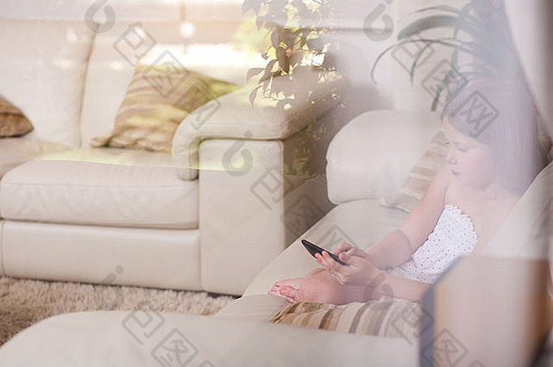 年轻的女孩坐着沙发电话生活房间玻璃窗口