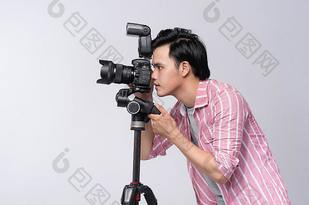 年轻的亚洲摄影师持有数字相机工作工作室