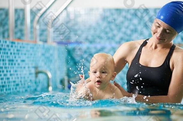年轻的细心的妈妈。帮助儿子游泳绿松石水游泳类婴儿婴儿溅水概念活跃的家庭休闲