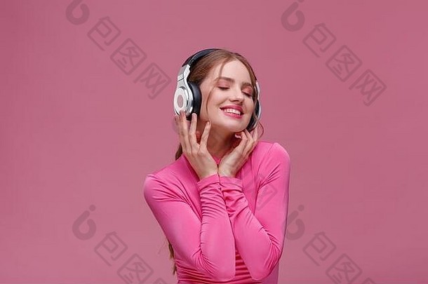 享受听音乐美丽的年轻的红色头发的人女人耳机听音乐有趣的微笑女孩耳机粉红色的上衣跳舞粉红色的