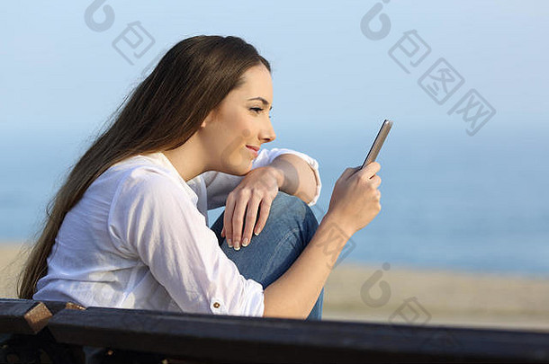 一边视图肖像放松女孩看聪明的电话内容海滩