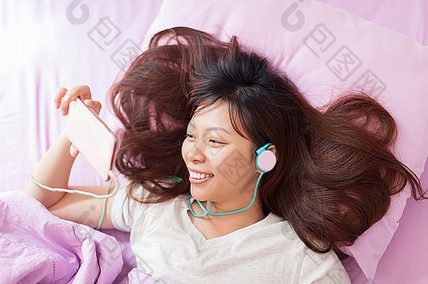 亚洲年轻的女孩聪明的电话穿耳机