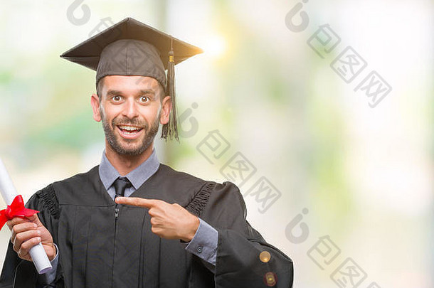 年轻的英俊的毕业男人。持有学位孤立的背景快乐指出手手指