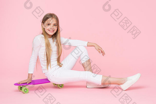 骑董事会风格年快乐孩子坐着董事会甲板粉红色的背景可爱的小溜冰者微笑紫罗兰色的一分钱董事会采取快乐滑板董事会