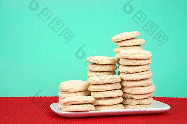糖饼干堆放多个高度白色矩形板红色的盘垫纸绿色背景