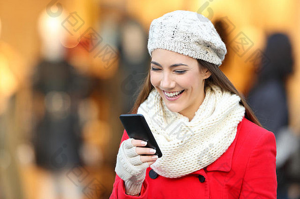 肖像快乐女人穿红色的外套阅读聪明的电话内容商业中心冬天