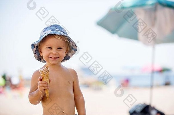 甜蜜的金发女郎蹒跚学步的男孩eaiting冰奶油海滩夏季