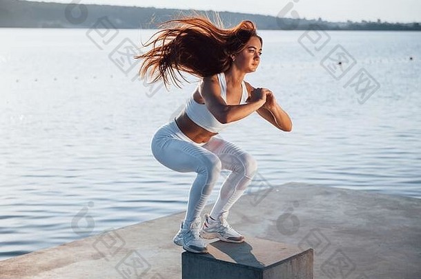 下蹲水泥多维数据集拍摄运动型女人健身练习湖白天