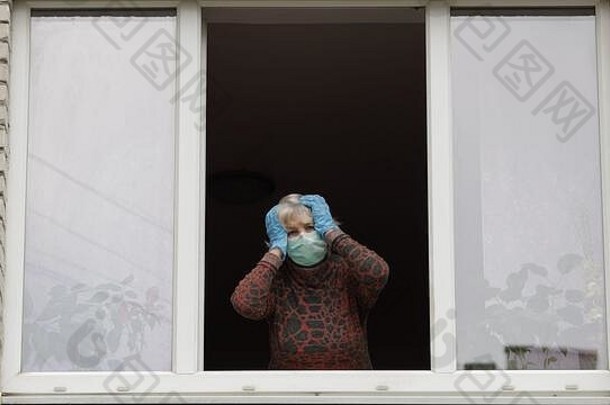女人恐慌保持窗口保护面具检查温度孤立的首页检疫病毒爆发老祖母科维德流感大流行冠状病毒社会距离