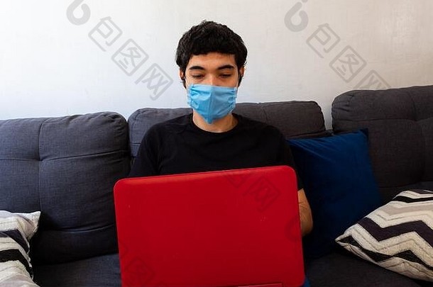 年轻的男人。穿蓝色的医疗面具工作首页移动PC由于科维德检疫