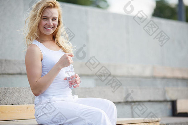金发女郎女孩白色衣服坐着板凳上休息