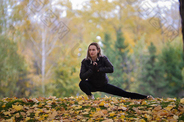 女孩体操运动员伸展运动腿秋天公园一边