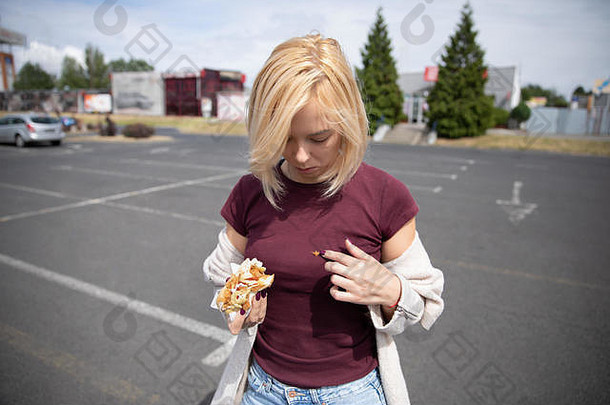 年轻的美丽的女孩吃热狗停车很多弄脏衣服不准确