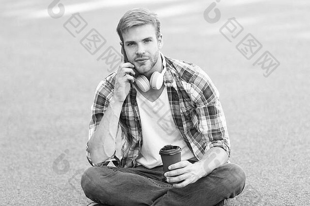 重要的调用电话调用听音乐电子书概念男人。网纹衬衫学生放松充电咖啡的家伙喝咖啡户外男人。坐地面无忧无虑的学生耳机