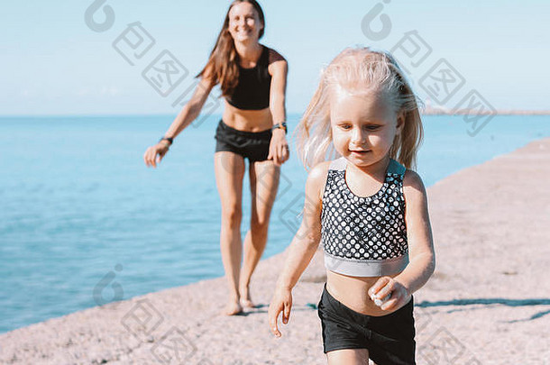 可爱的女孩适合妈妈海滩健康的生活方式体育运动家庭