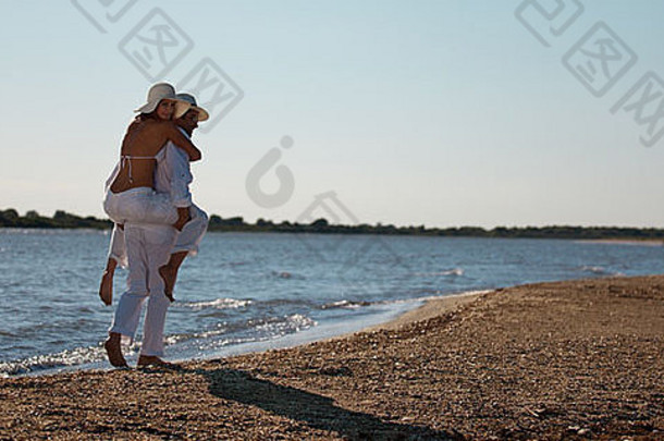 快乐年轻的夫妇穿着白色海滩小猪回来骑