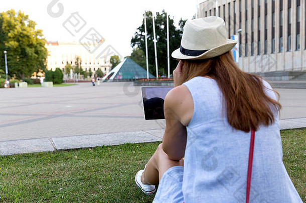 视图美丽的年轻的女人回来听音乐耳机坐着在户外公园