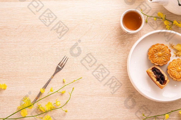 美味的月亮蛋糕中秋节日明亮的木表格概念节日下午茶装饰黄色的花前视图平躺