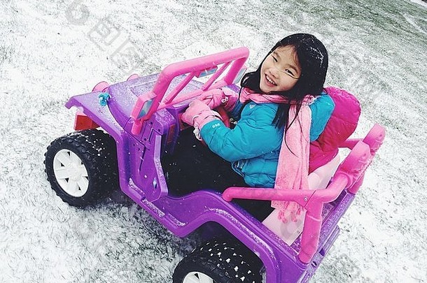 年轻的女孩骑玩具车雪