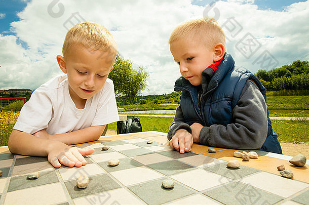 国际跳棋董事会游戏男孩聪明的孩子们孩子们玩跳棋思考户外公园童年发展