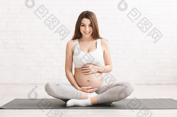 活跃的怀孕了女人坐着地板上体育