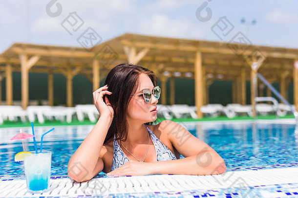 十美丽的女人比基尼桑拉斯坐着游泳池鸡尾酒时尚肖像优雅的女人比基尼太阳镜