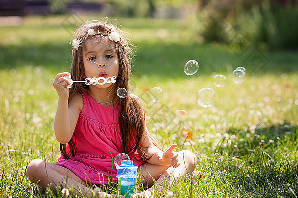 美丽的肖像甜蜜的可爱的女孩吹肥皂泡沫公园夏季