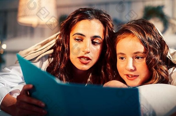 年轻的漂亮的女孩床上圣诞节早....快乐家庭微笑生活方式假期阅读书