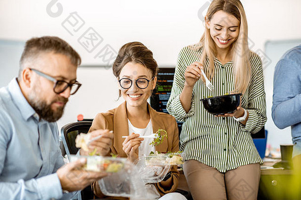 集团多样化的的同事们吃外卖沙拉坐着有趣的午餐时间办公室