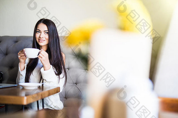 年轻的女人喝咖啡移动PC电脑咖啡商店