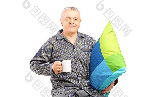 成熟的男人。睡衣持有咖啡杯子枕头孤立的白色背景