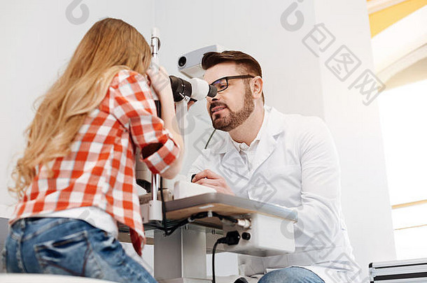 集中勤奋的眼科医生观察病人眼睛