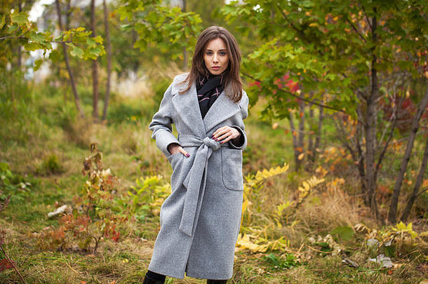 年轻的浅黑肤色的女人女人灰色的羊毛外套背景秋天公园