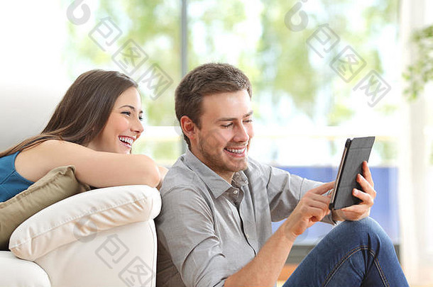 快乐的夫妇平板电脑行坐着生活房间首页窗口背景